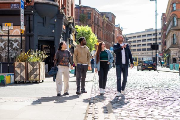 Group of 4 people walking on cobbled street in Manchester