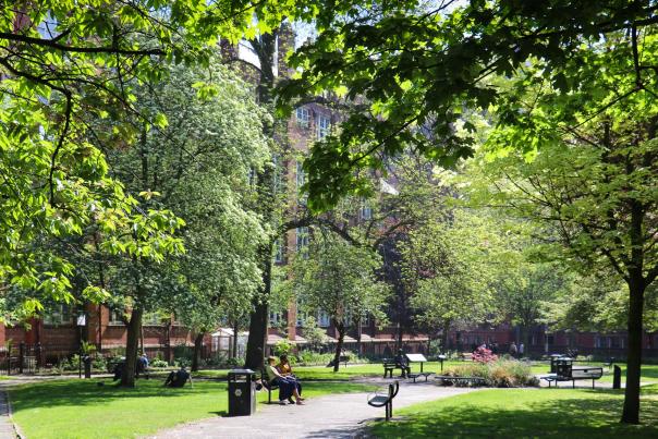 Gardens with people sat on benches within trees