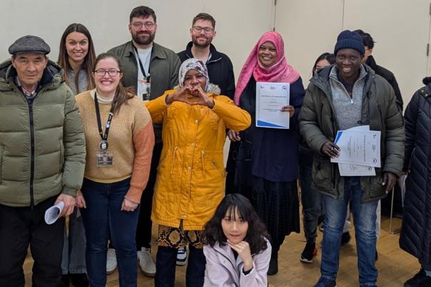 A group of refugees stand together smiling with Hull Truck staff