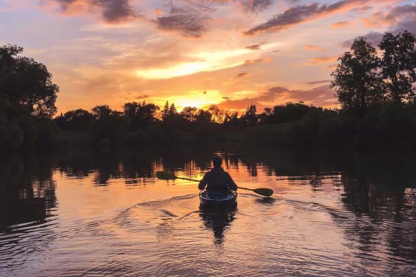 person kayaking on red river at sunset