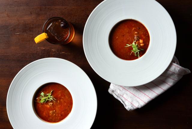 Bowl of red chile bison posole with hominy and tender bison in rich red broth.