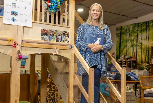 Rayna Dineen stands on the wooden staircase inside Reading Quest's Santa Fe center.