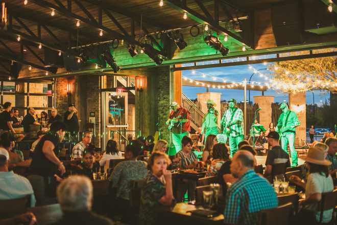 People at a restaurant with open patio concert at Texas Live!