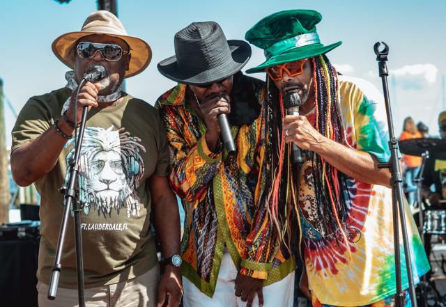 Three black men singing on a stage at a festival