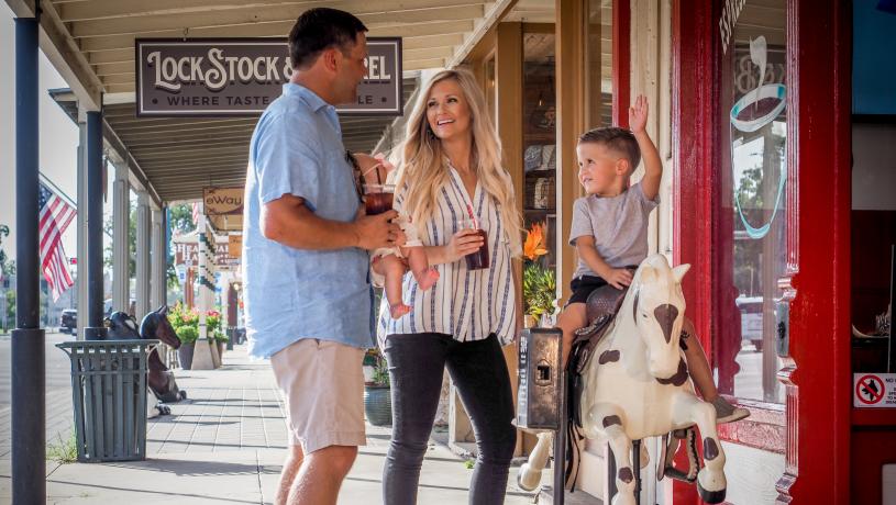 A family on Fredericksburg, TX Main Street, with son riding a horse amusement ride