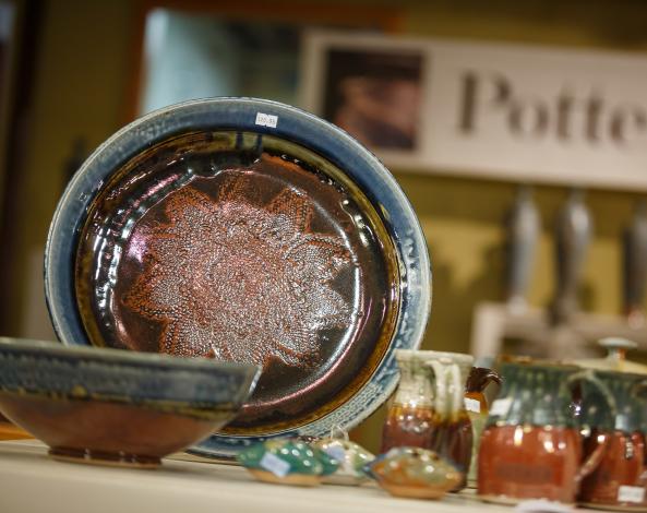 A handmade ceramic platter, along with cups and bowls, on display at Goertzen Pottery.