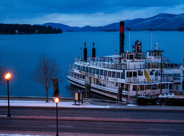 A white steamboat docked at dusk in winter in Lake George