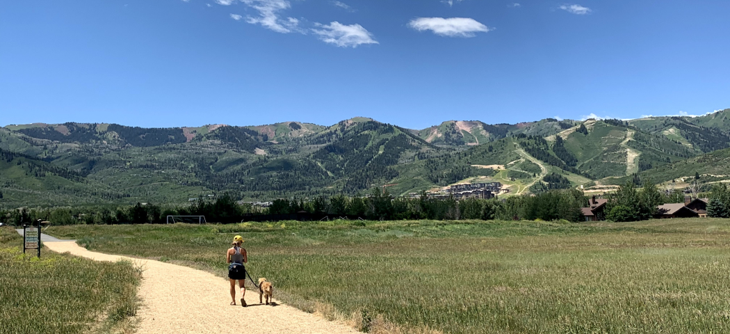 Woman walking with her dog with scenic mountains in background
