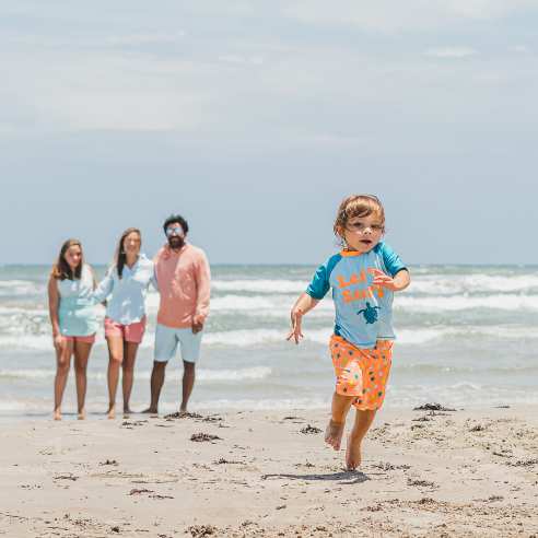 A family watches a toddler run across the beach in Port Aransas, Texas