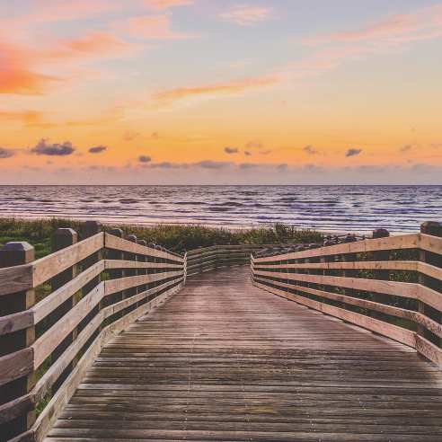 A wooden boardwalk leading to the beach at sunrise