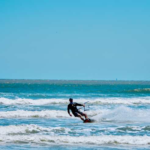 Man kite boards on blue water