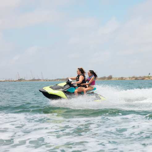 Woman and girl ride on a green jet ski