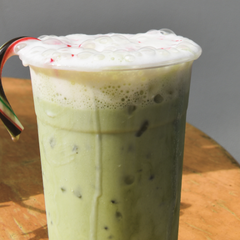 A green matcha latte with a candy cane sits on a table
