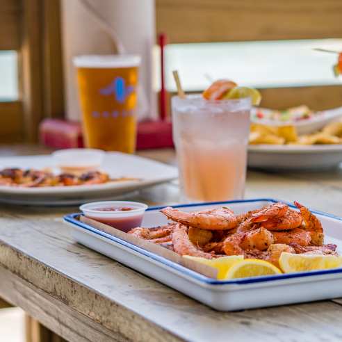 A plate of seafood on a table outside on a deck overlooking the water.