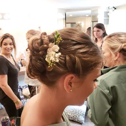 A girl's hairstyle with flowers is in focus with others in background