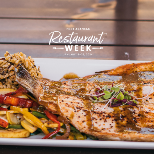 A plate with a large fish with a tail attached and sides of rice and mixed vegetables. Over the plate is a white logo reading "Port Aransas Restaurant Week January 19–28, 2024"