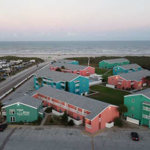 Aerial view of a group of brightly colored condos leading to the beach.