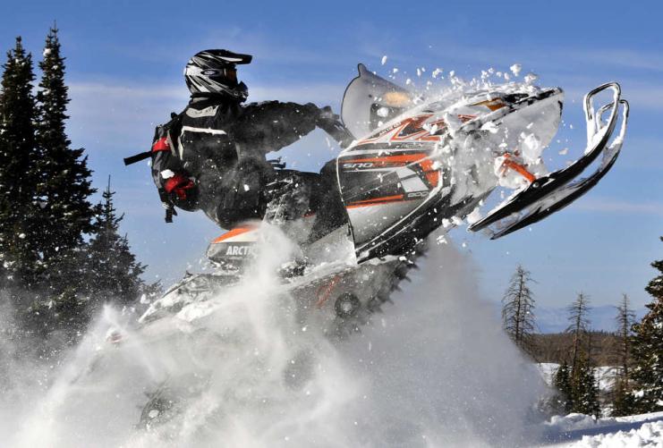 Snowmobiler jumping in Utan snow