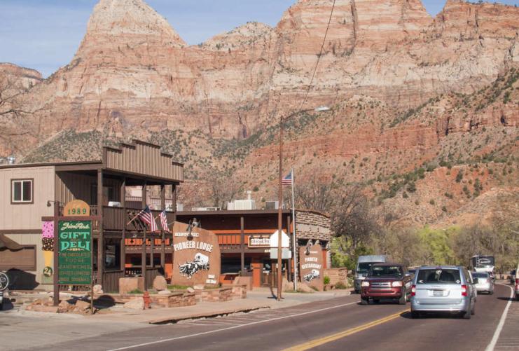 Cars driving past shops in Springdale Utah near the entrance to Zion