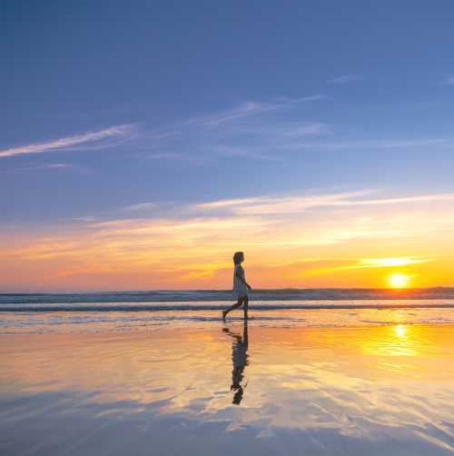 Lady walking on the beach at sunrise