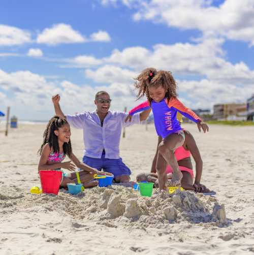 Family on beach smashing a sandcastle