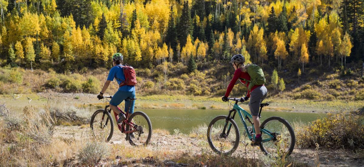 Two people mountain biking with fall foliage in background