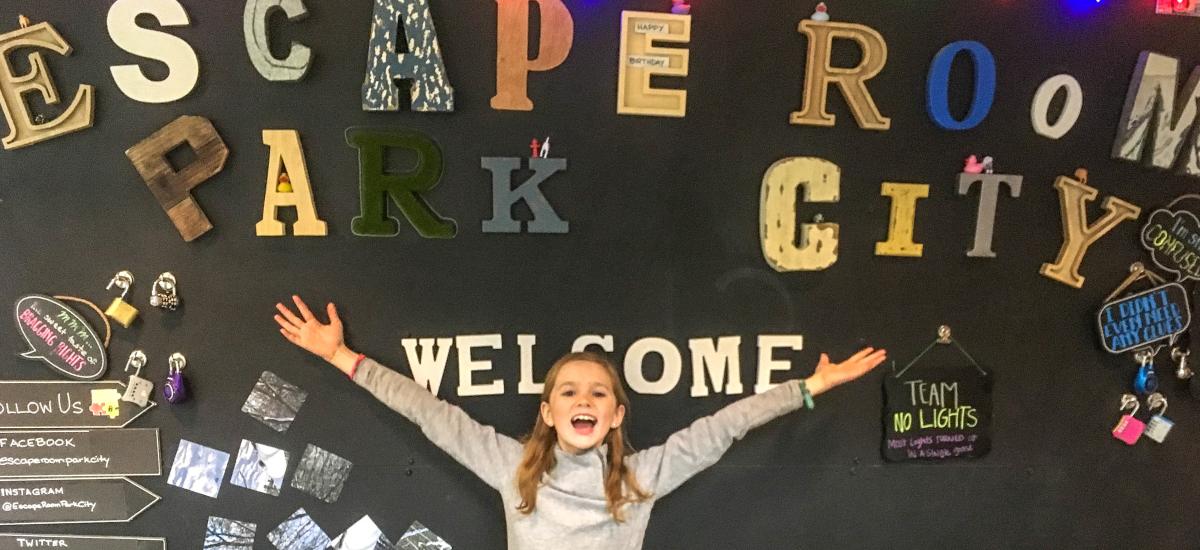Girl stands in front of a sign that reads escape room