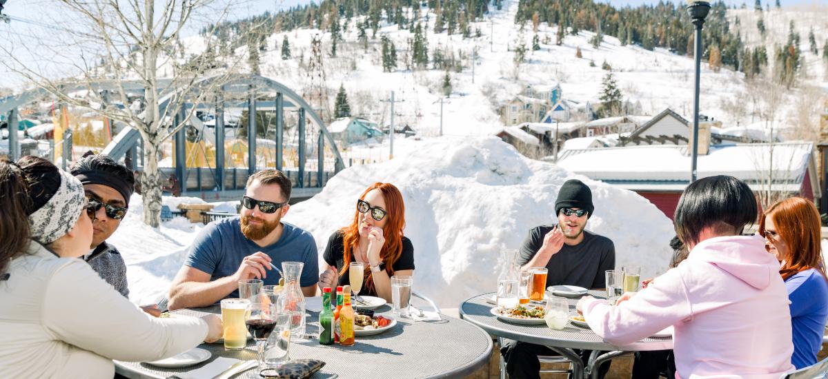 Group of friends eating at bridge on the patio on a spring day apres ski