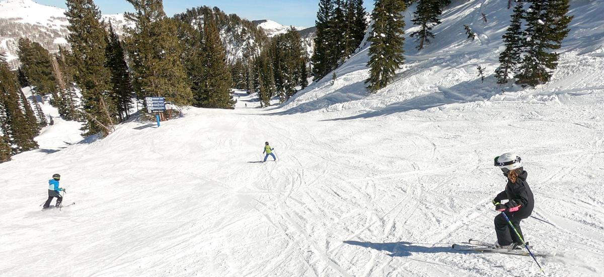Three kids skiing down a mountain