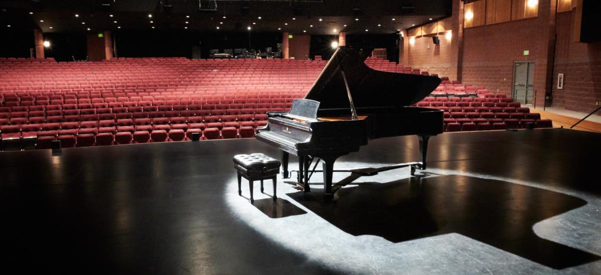 Photo of a piano in an empty theater