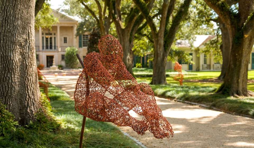 A wire sculpture sits in an outdoor garden
