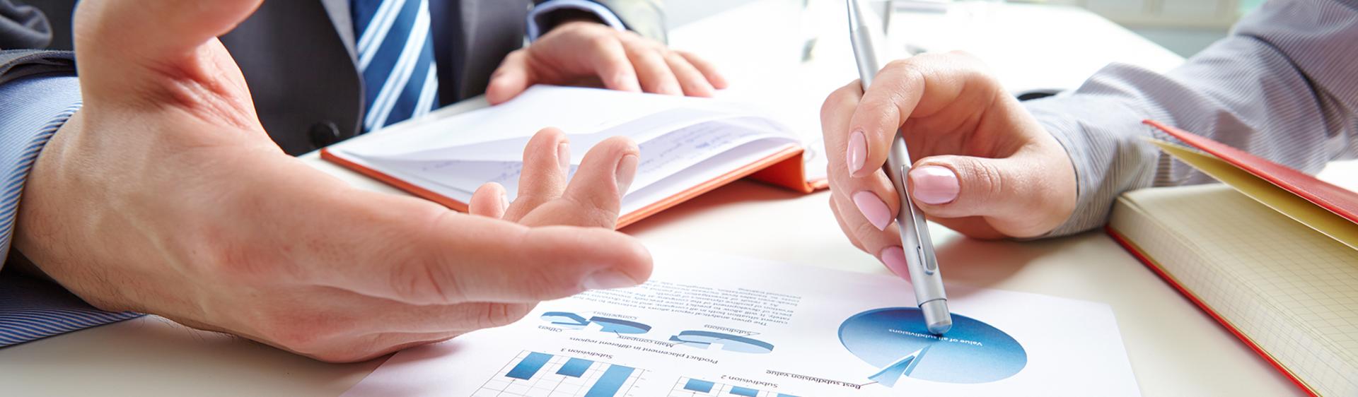 Two people discussing a paper full of charts.