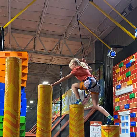 A girl climbing an obstacle course at Urban Air