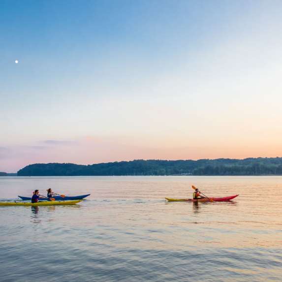 Three kayaks on Monroe Lake during sunset
