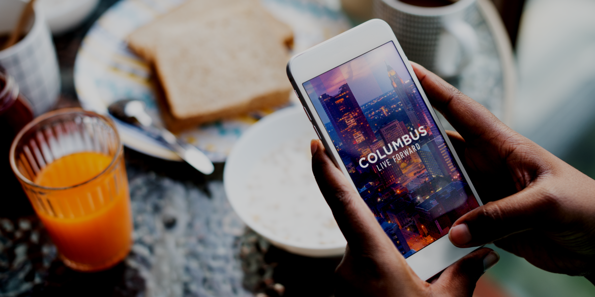 The Columbus Experience App shows on a mobile phone at the breakfast table