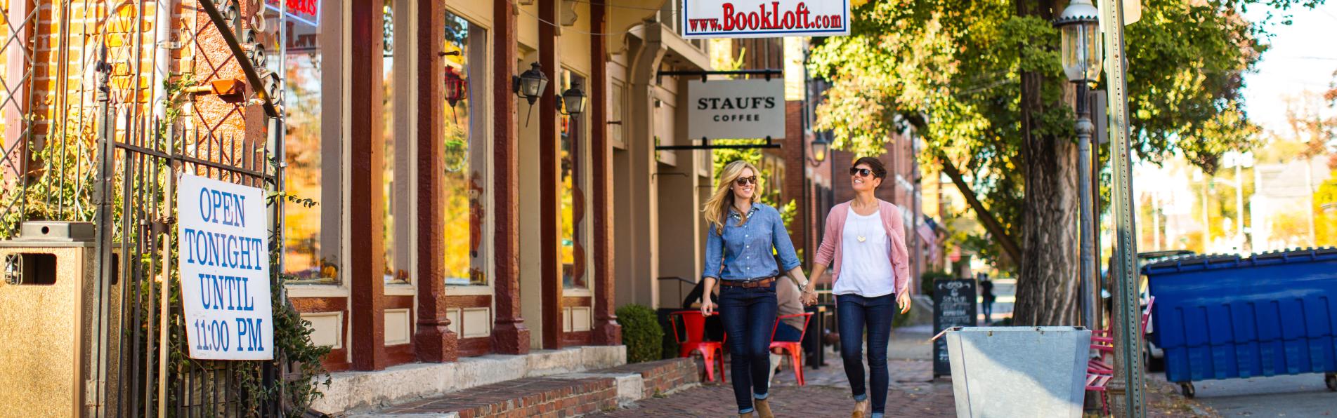 Two women walking and holding hands by the Book Loft in German Village