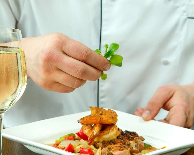 A chef placing a garnish on a plate of food