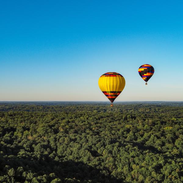 Two hot air balloons floating over Bloomington's rolling hills
