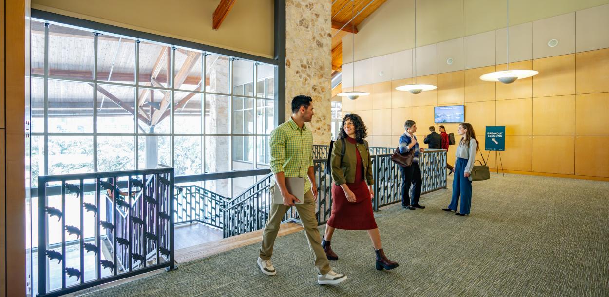 Image of a group of people dressed in business casual walking into the Palmer Events Center and chatting with one another.