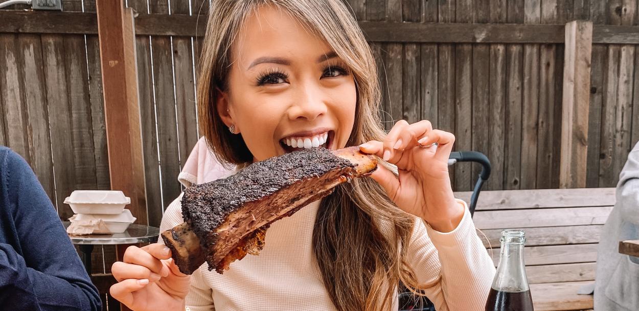 Woman bites into bbq ribs at la Barbecue food truck in Austin Texas