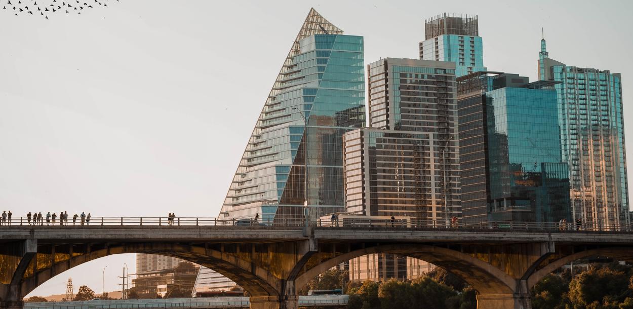 Austin city skyline with birds flying over a bridge at Lady Bird Lake