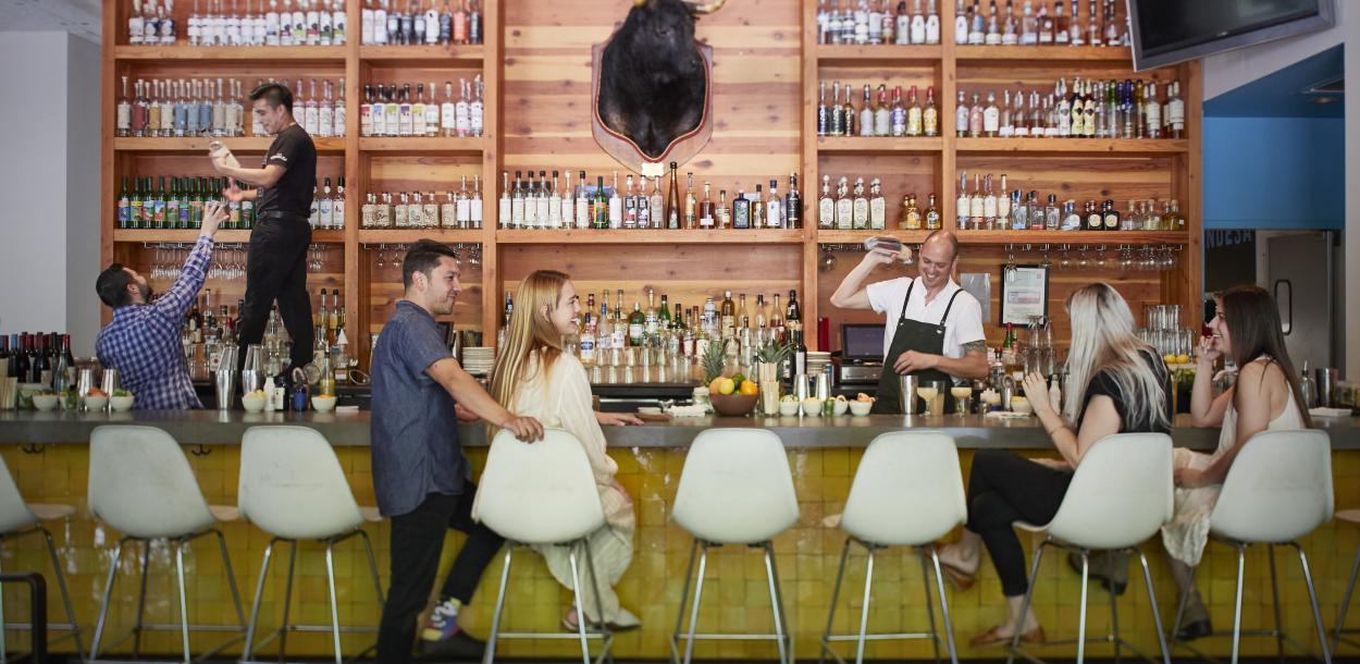 People sitting at bar while bartender shakes cocktail at La Condesa Bar in Austin Texas