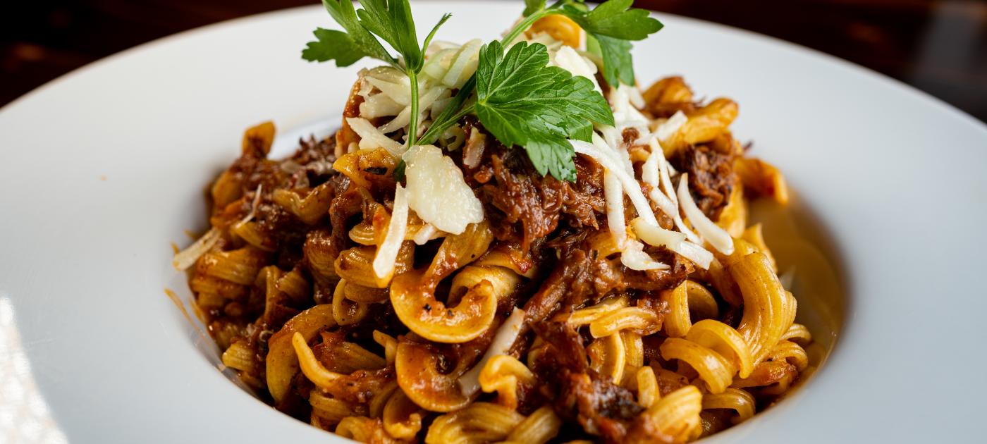 A pasta dish served in a white bowl and garnished with parsley.