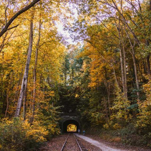 A couple bikes through the historic Howard Tunnel on the rail trail during autumn