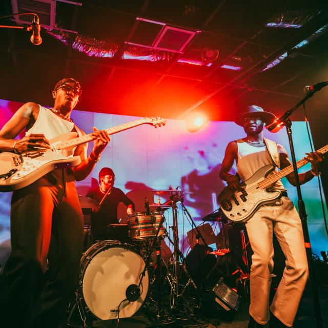 Band on stage with bright, colorful lights shining on them.