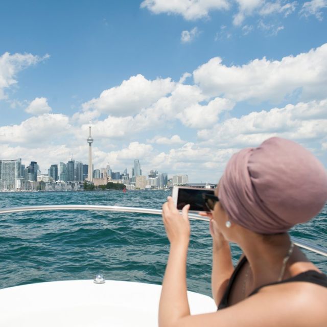 A person takes a photo of the Toronto skyline from a boat on Lake Ontario