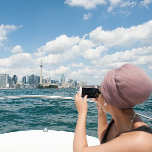 A person takes a photo of the Toronto skyline from a boat on Lake Ontario