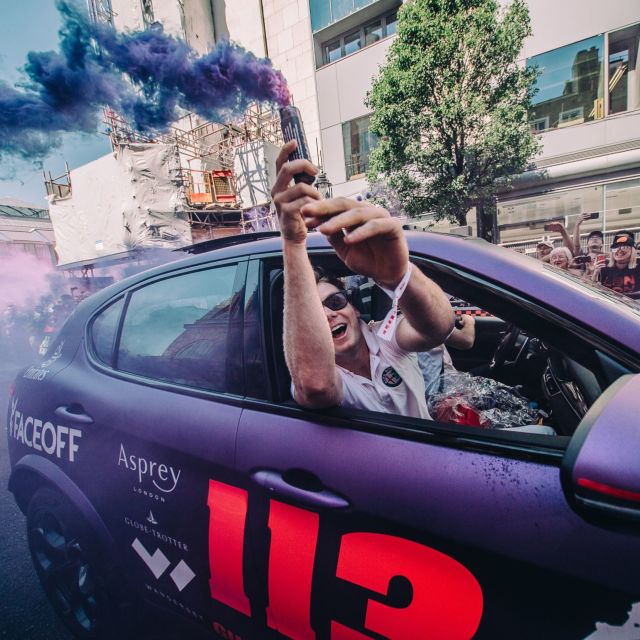 A passenger leans out of a purple car