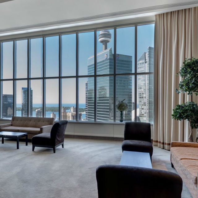Meeting room with a couch, coffee table and chairs overlooking window with skyline