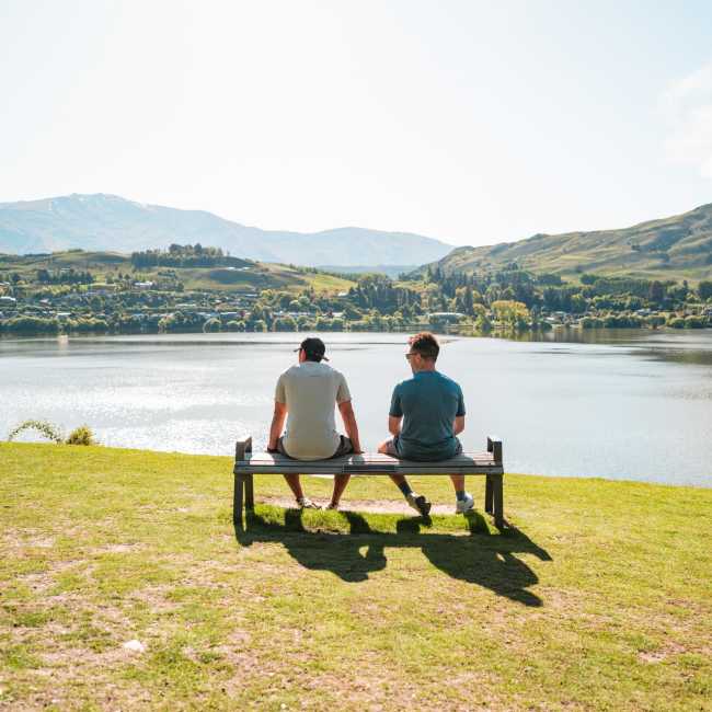 People people sitting on a bench overlooking Lake Hayes